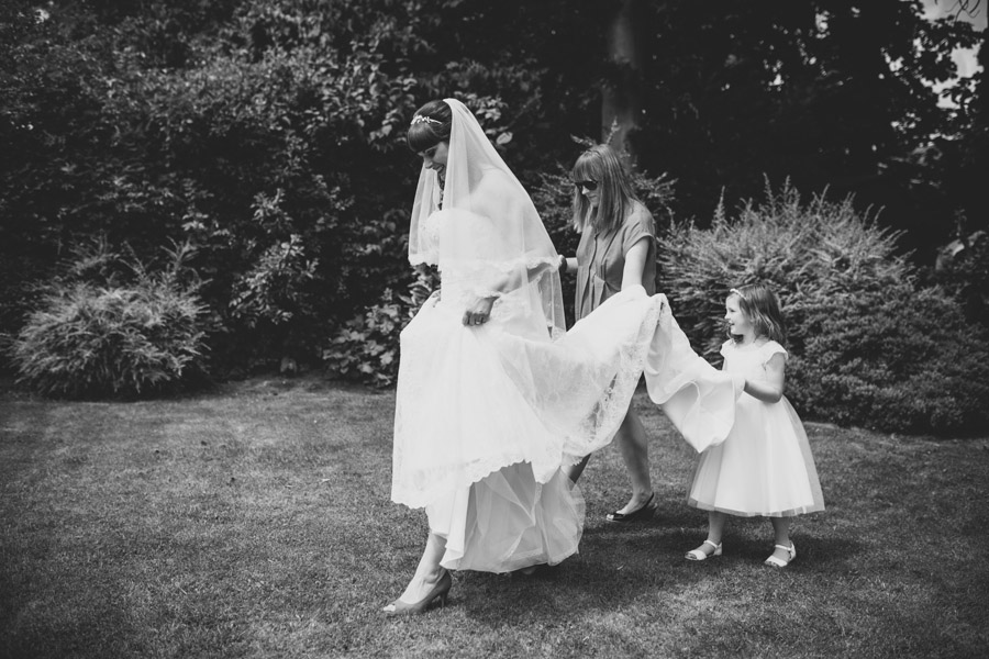 bride with flower girl holding dress