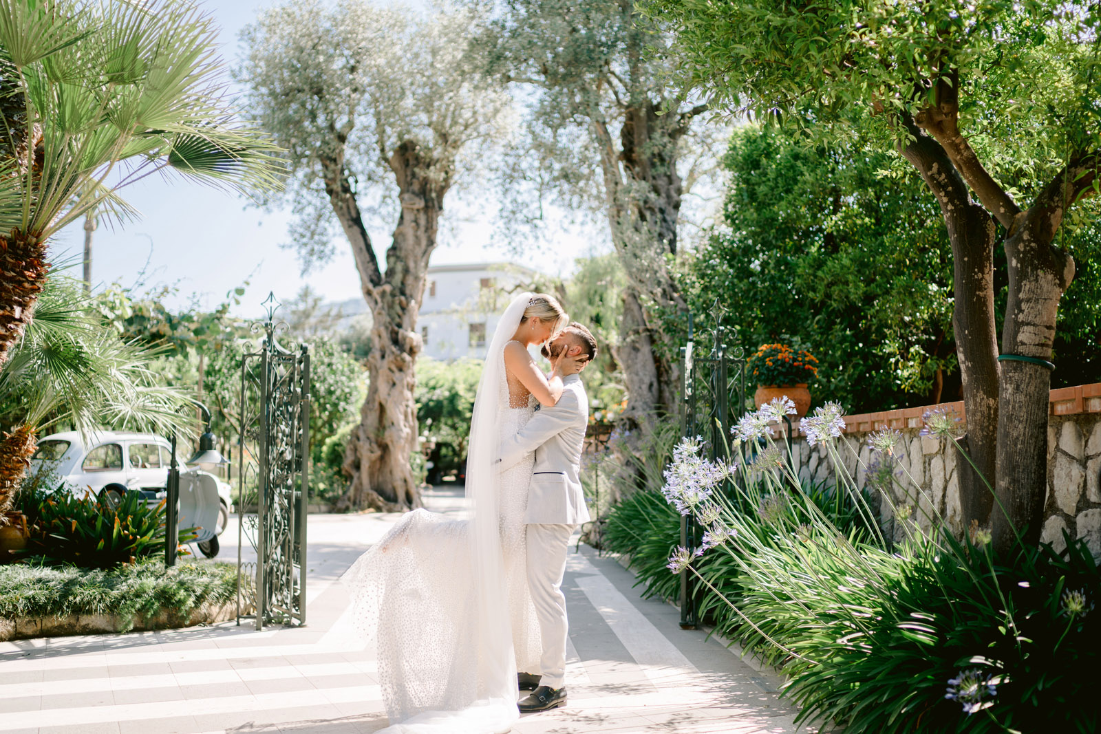 bride and groom at villa antiche mura on their wedding day kissing in the gardens and bride is lifted in the air