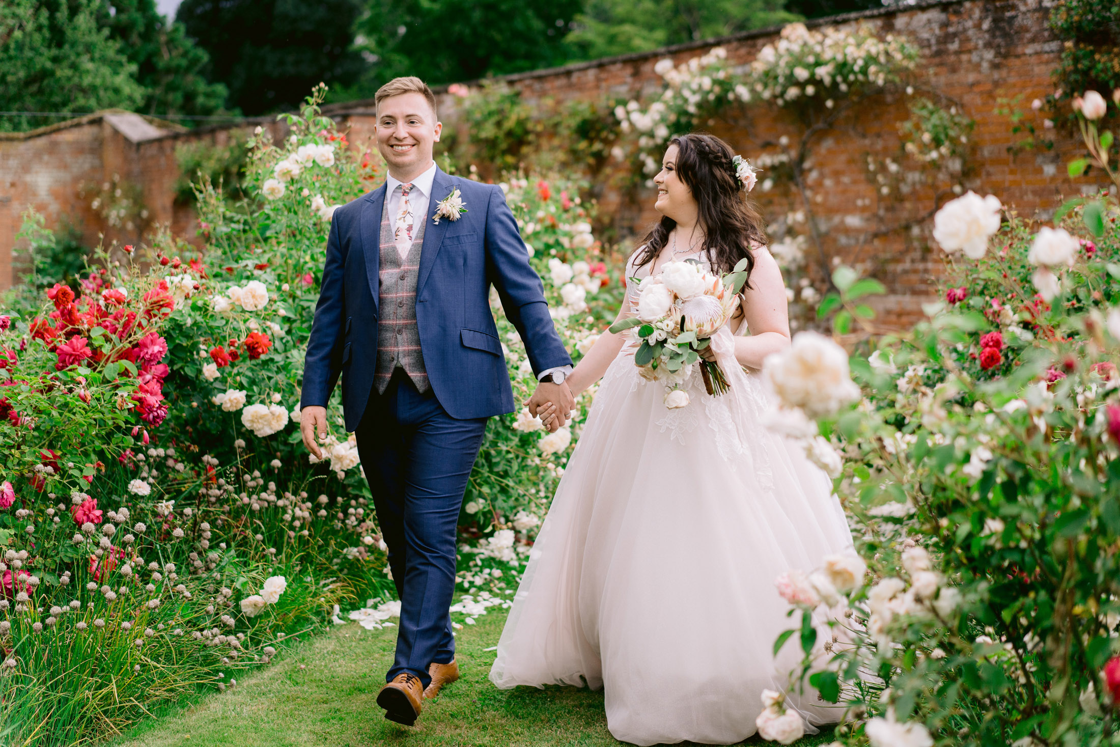 bride and groom walking in the combermere abbey gardens