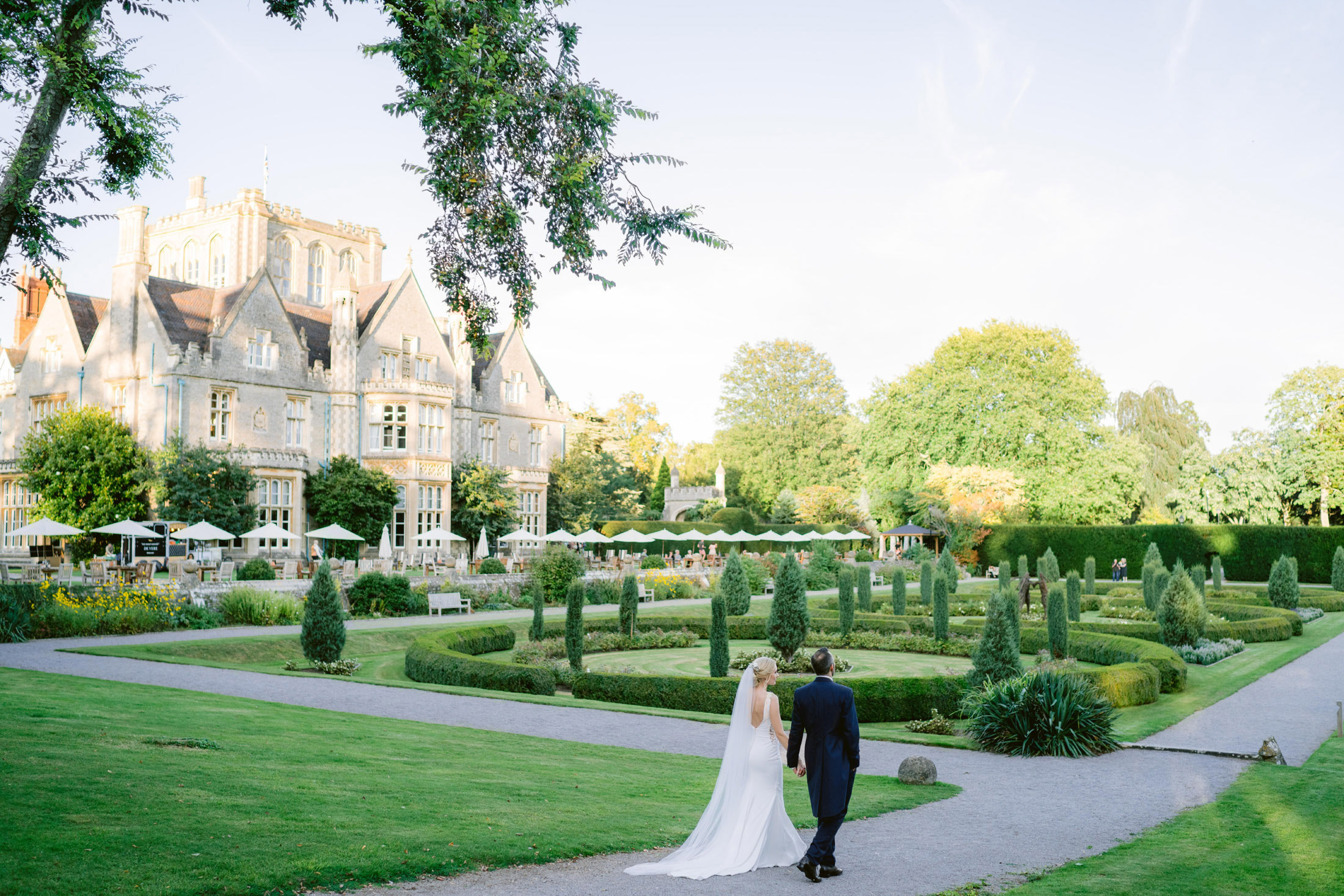 bride and groom walking in the gardens of tortworth court hotel on their wedding day