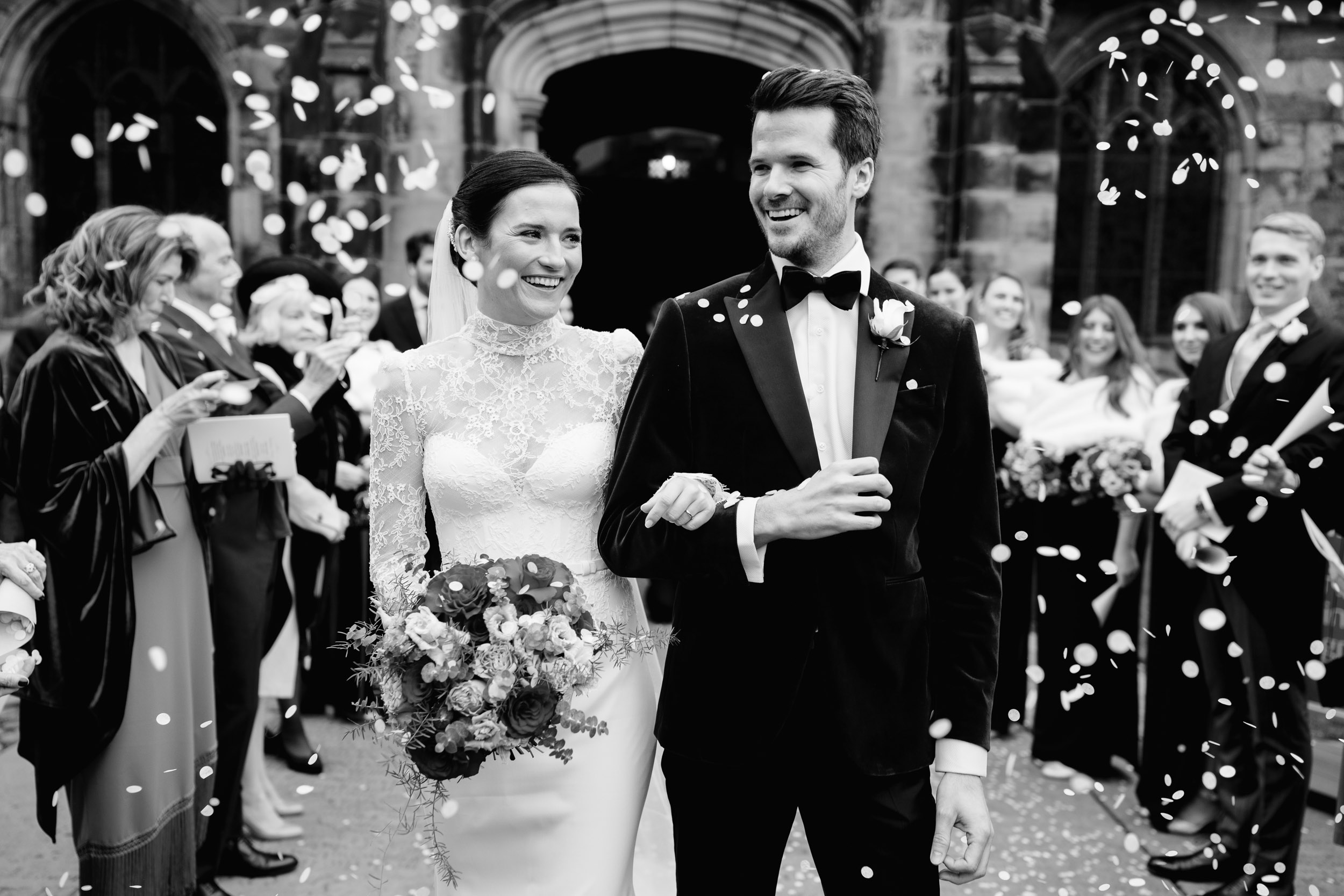 bride and groom walking through line of confetti at peckforton castle wedding