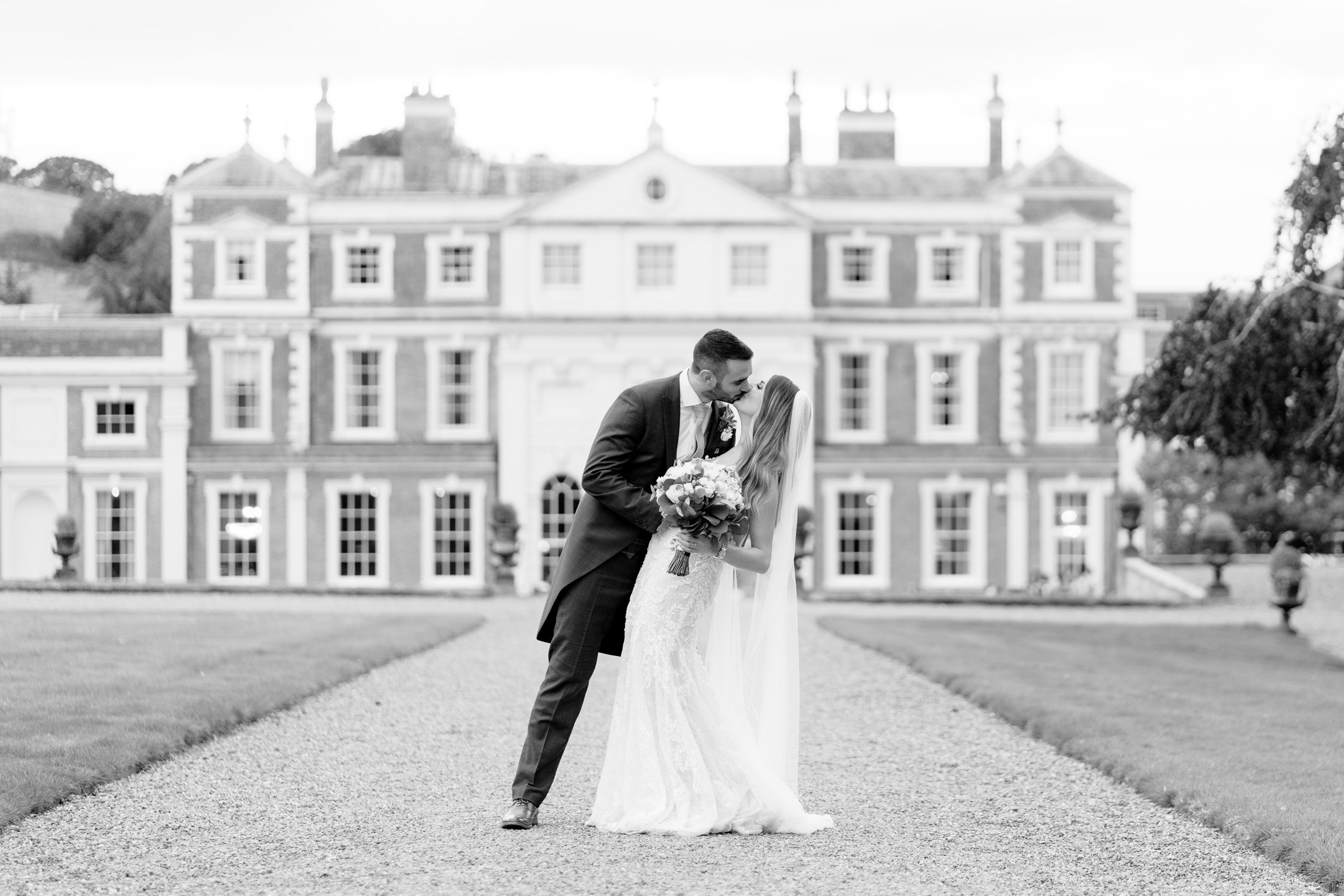wedding couple kissing with hawkstone hall in the background